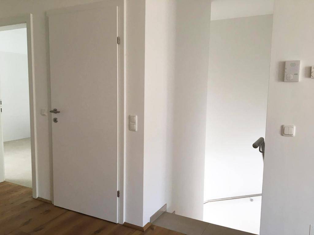 Eingangsbereich mit Holzboden und weißen Türen, der zu weiteren Räumen führt.