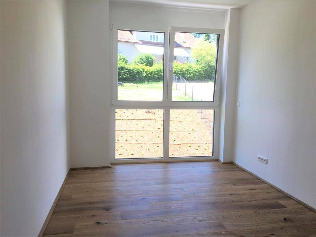 Schlafzimmer mit großen Fenstern, die viel Tageslicht hereinlassen und einen Blick ins Grüne bieten.
