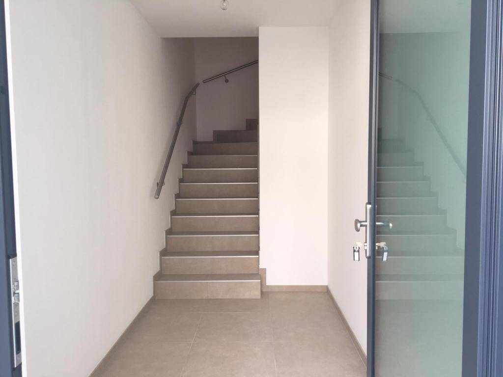 Treppenhaus mit Fliesenboden und Handlauf, das zu den oberen Etagen führt.