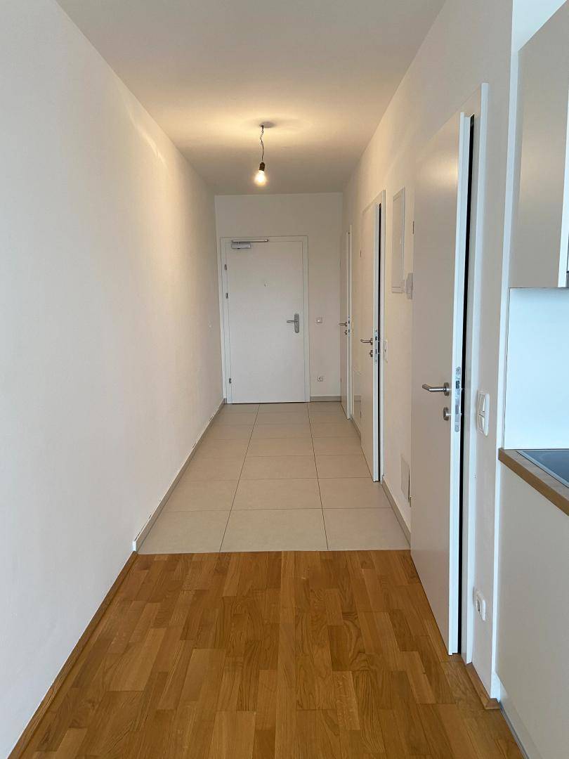 Heller Flur mit Fliesenboden, der in Parkett übergeht, und mehreren Türen zu den Zimmern.