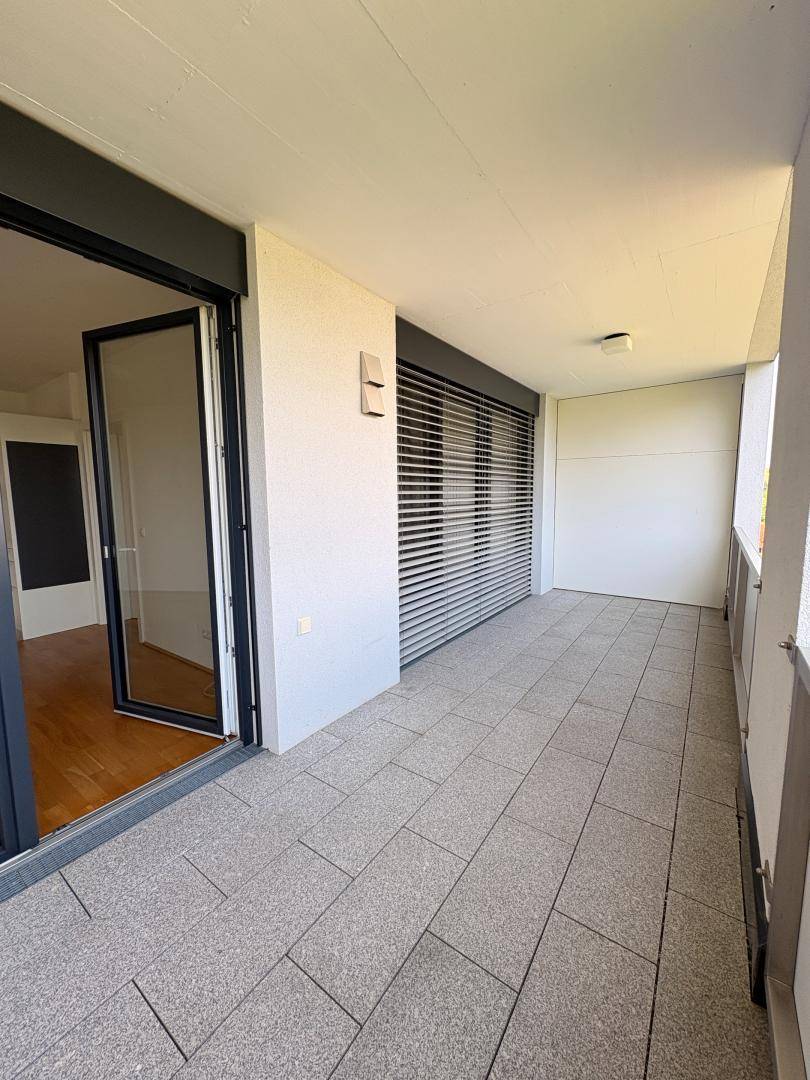 Balkon mit Fliesenboden und geschlossenen Rollläden, der Privatsphäre und Sonnenschutz bietet.