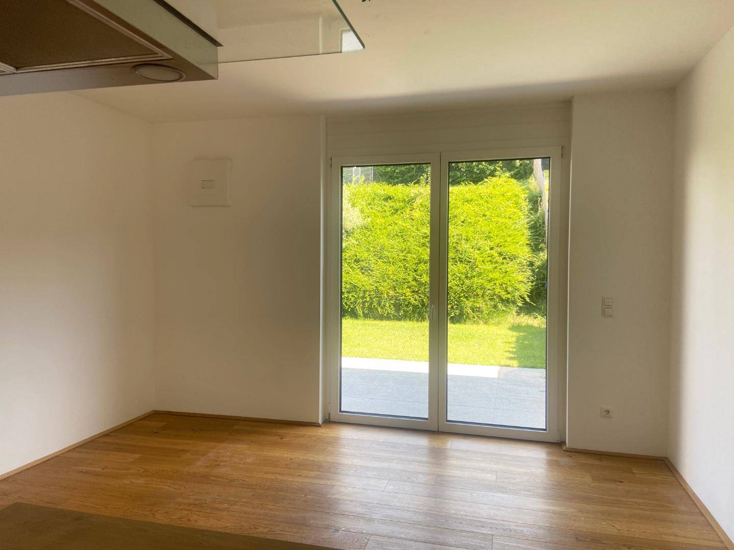 Heller Wohnraum mit großen Fenstern und Blick ins Grüne.