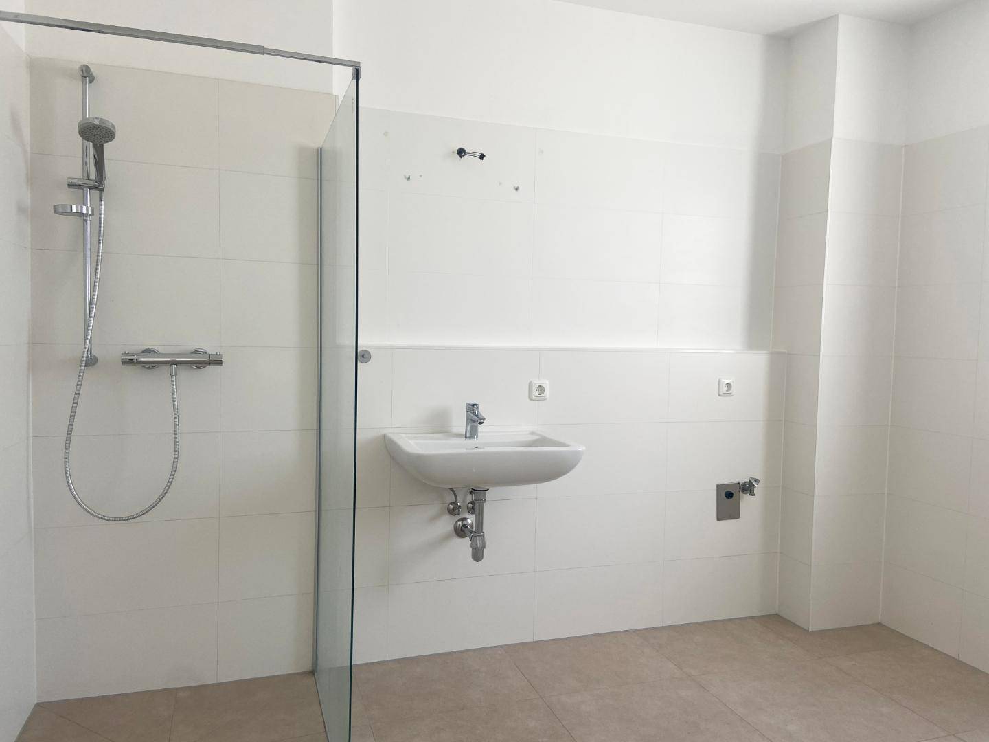 Modernes Badezimmer mit Dusche, Waschbecken und weißen Fliesen.