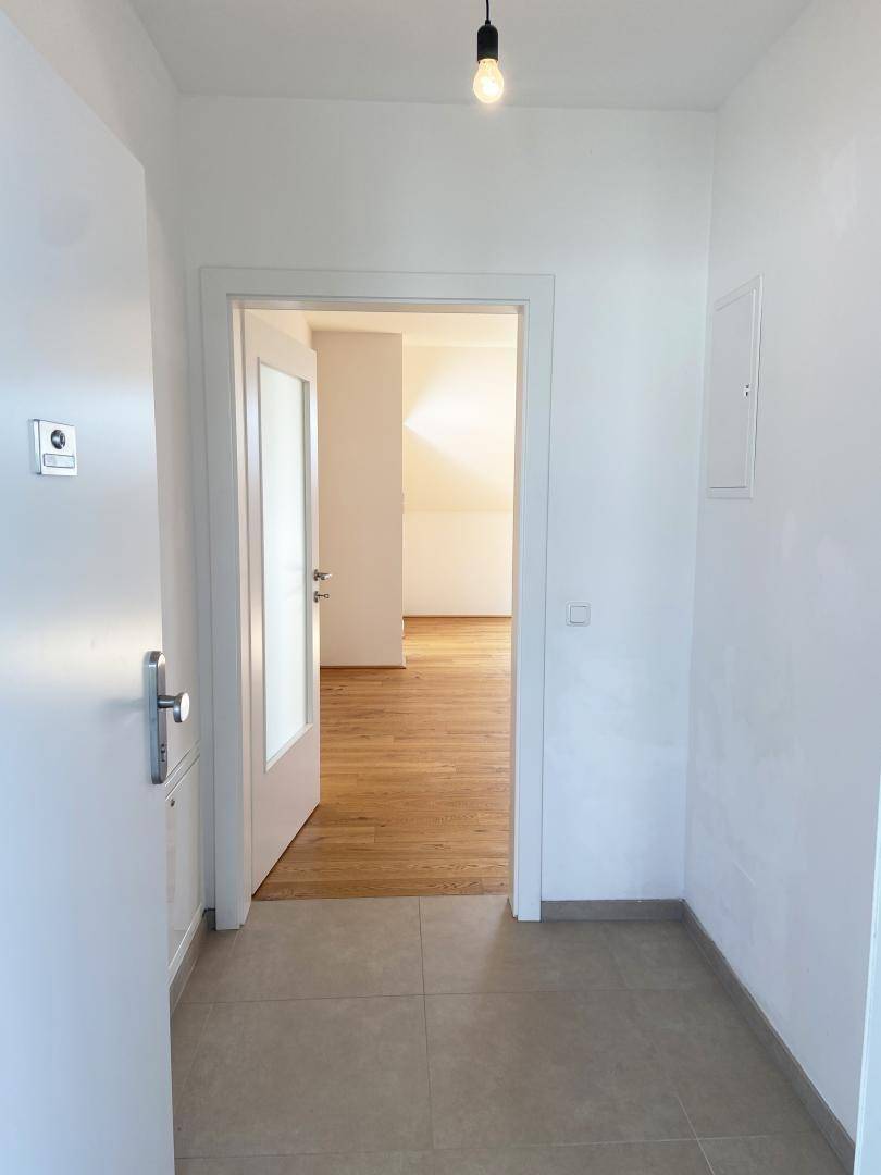 Heller Eingangsbereich mit Fliesenboden und Zugang zu den Wohnräumen mit Holzboden.
