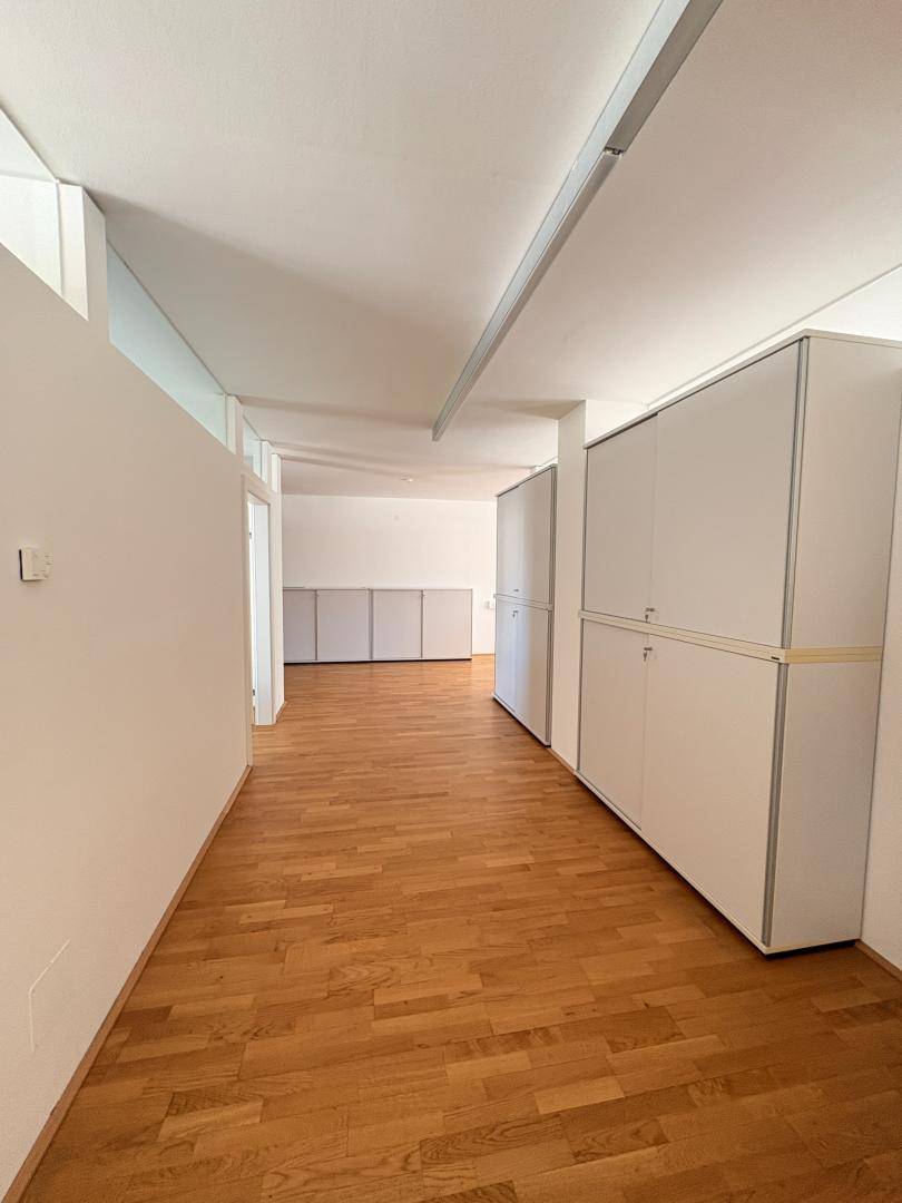 Langer Flur mit Holzboden und weißen Wänden, gesäumt von praktischen Einbauschränken für Stauraum.