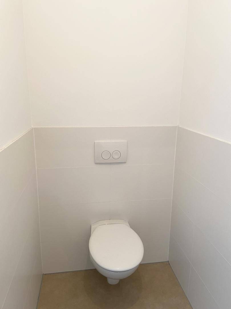 Modernes Gäste-WC mit wandhängender Toilette und hellen Fliesen, sehr sauber und funktional.