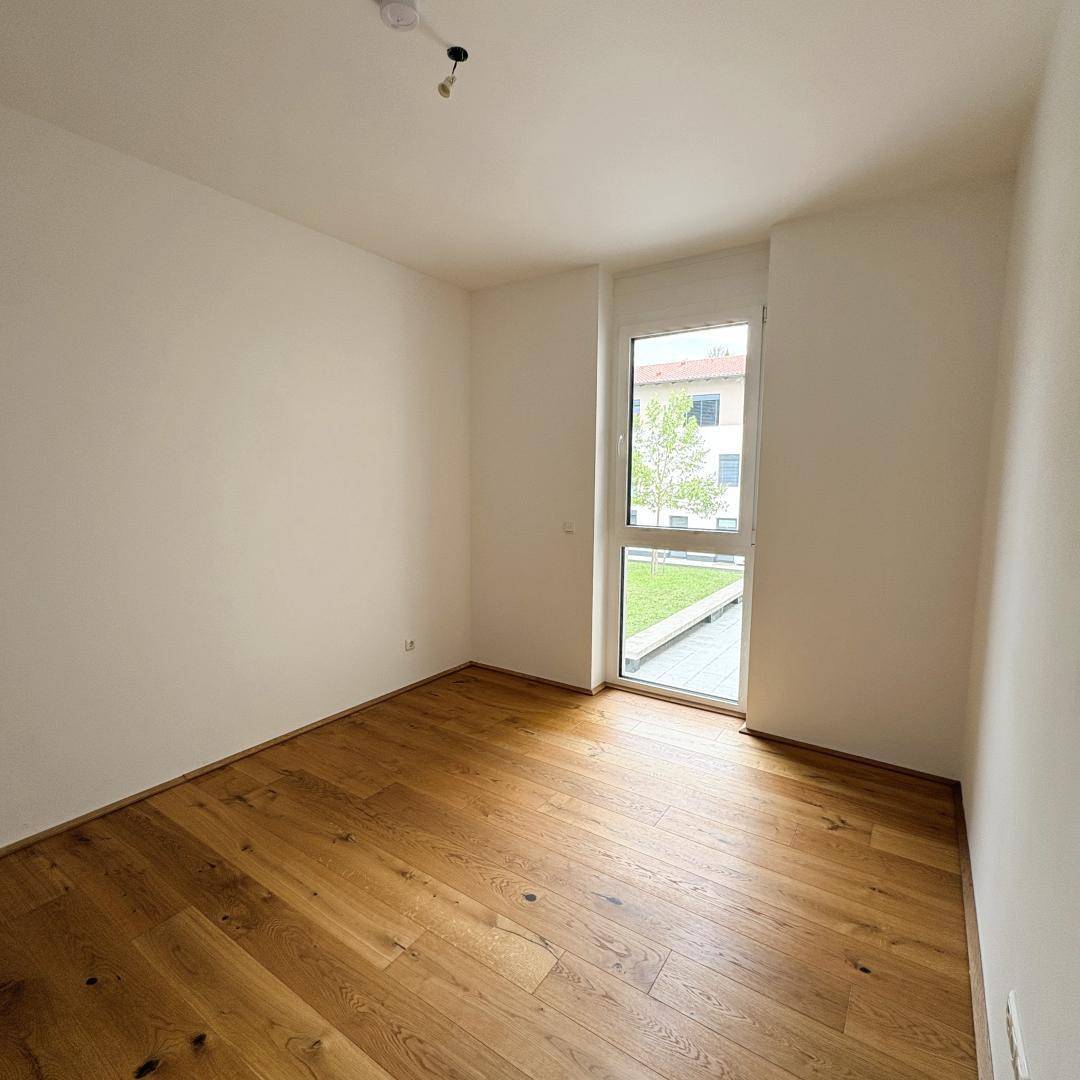 Helles Zimmer mit Parkettboden und direktem Zugang zu einem kleinen Außenbereich.