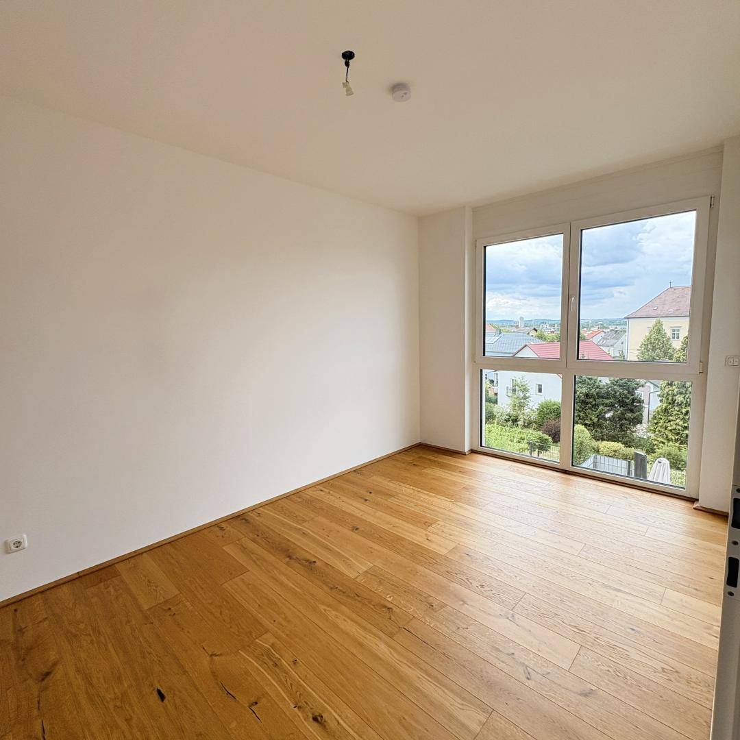 Geräumiges Zimmer mit Parkettboden und weitem Blick über die umliegende Wohngegend.