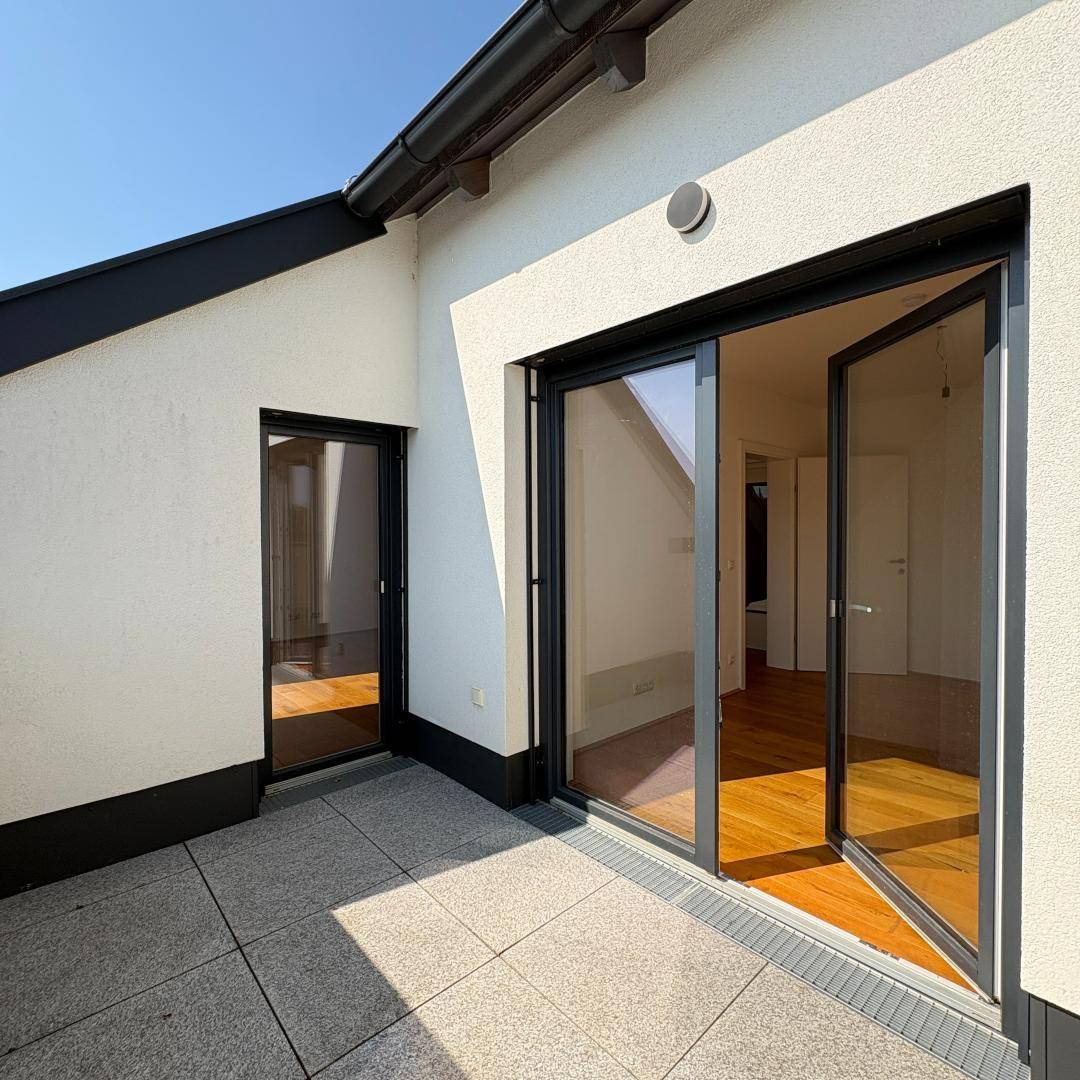 Geräumige Dachterrasse mit Fliesenboden und Zugang zu den Innenräumen, sonniger Bereich.