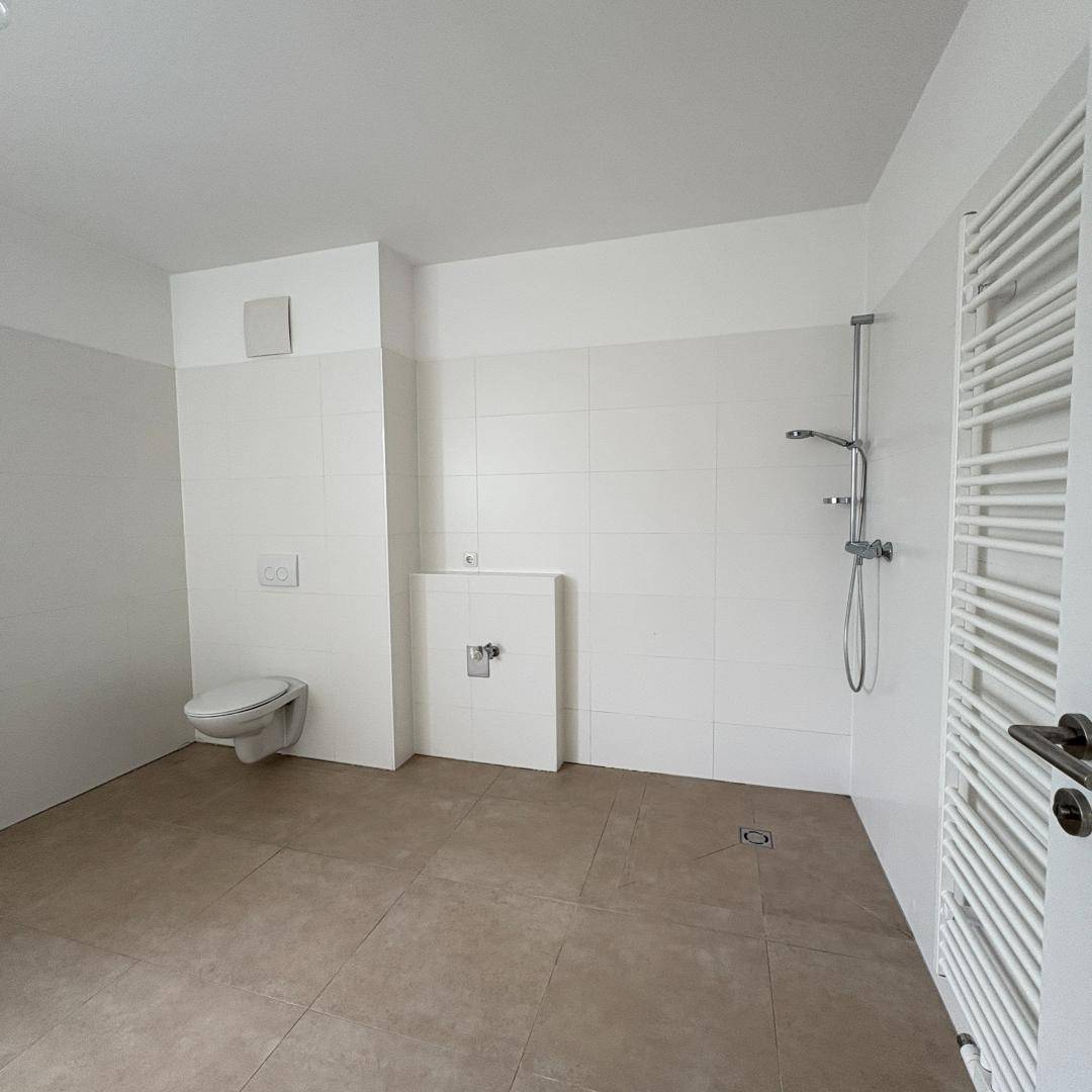 Modernes Badezimmer mit bodengleicher Dusche, Wand-WC und beheiztem Handtuchhalter.