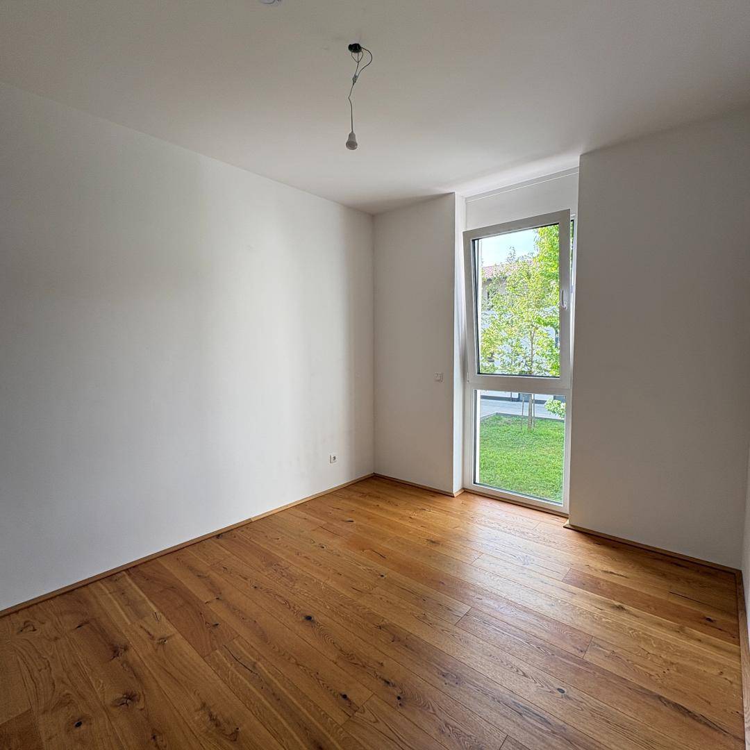 Helles Zimmer mit großen Fenstern und Blick auf die grüne Außenanlage.