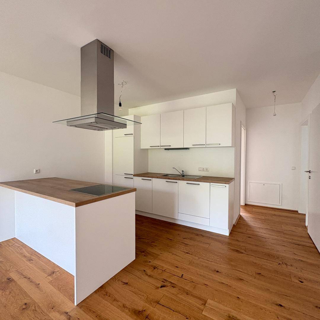 Helle, moderne Küche mit weißen Fronten, Holz-Arbeitsplatte und Kochinsel.