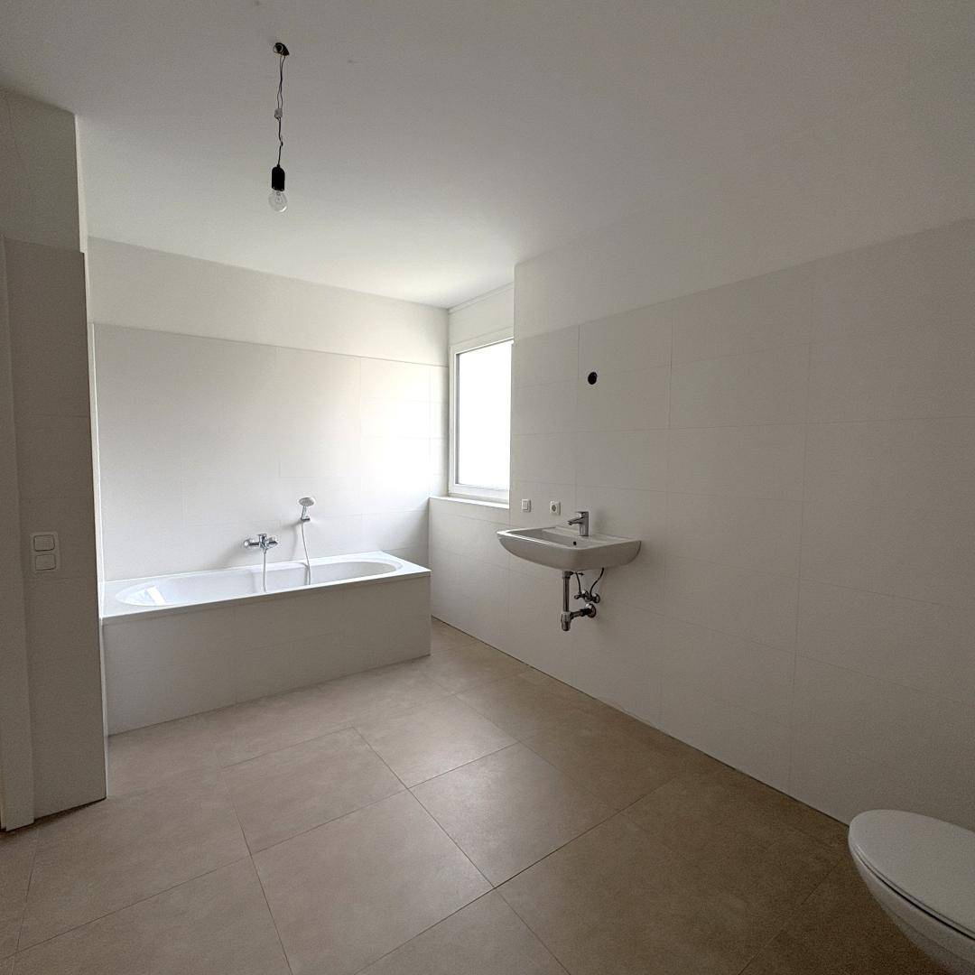 Geräumiges Badezimmer mit Badewanne, Waschbecken, WC und Fenster für Tageslicht.