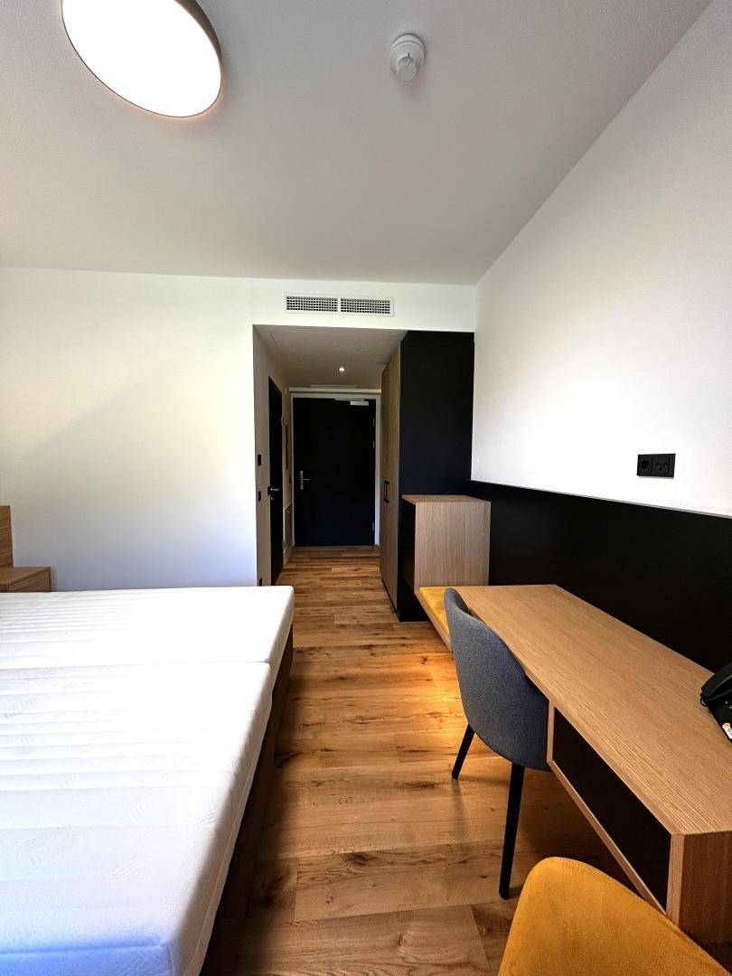 Schlafzimmer mit Holzboden und Blick auf den Eingangsbereich mit Schrank und Tür.