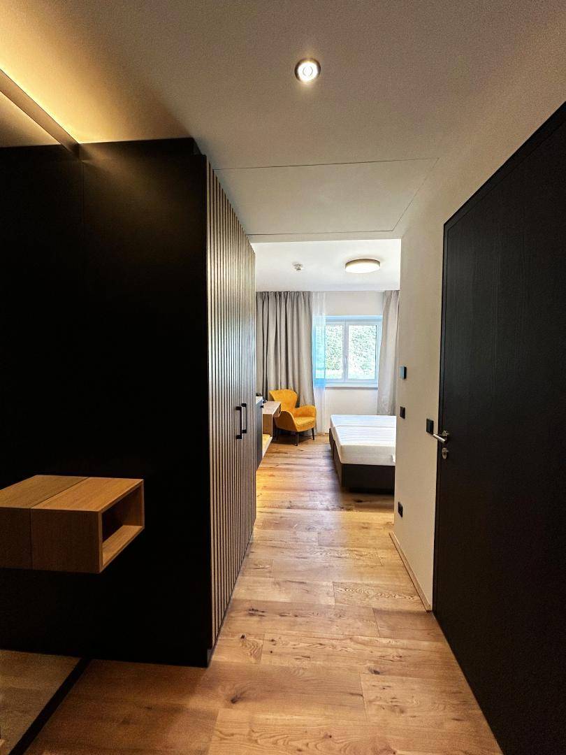 Flur mit Holzboden und integrierten Schränken, der zum Schlafzimmer führt.