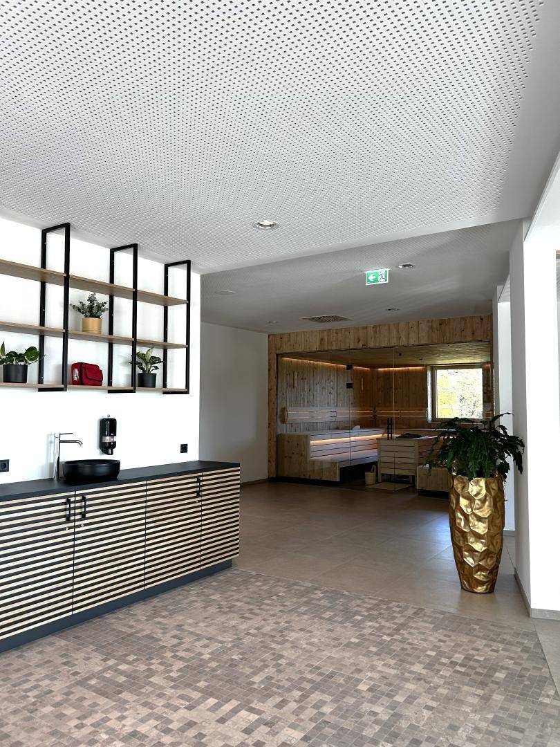 Empfangsbereich des Wellnessbereichs mit Theke und Blick auf die Sauna.