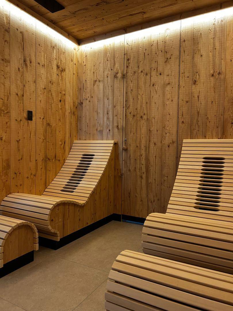 Entspannungsbereich mit ergonomischen Holzliegen und indirekter Beleuchtung in der Sauna.