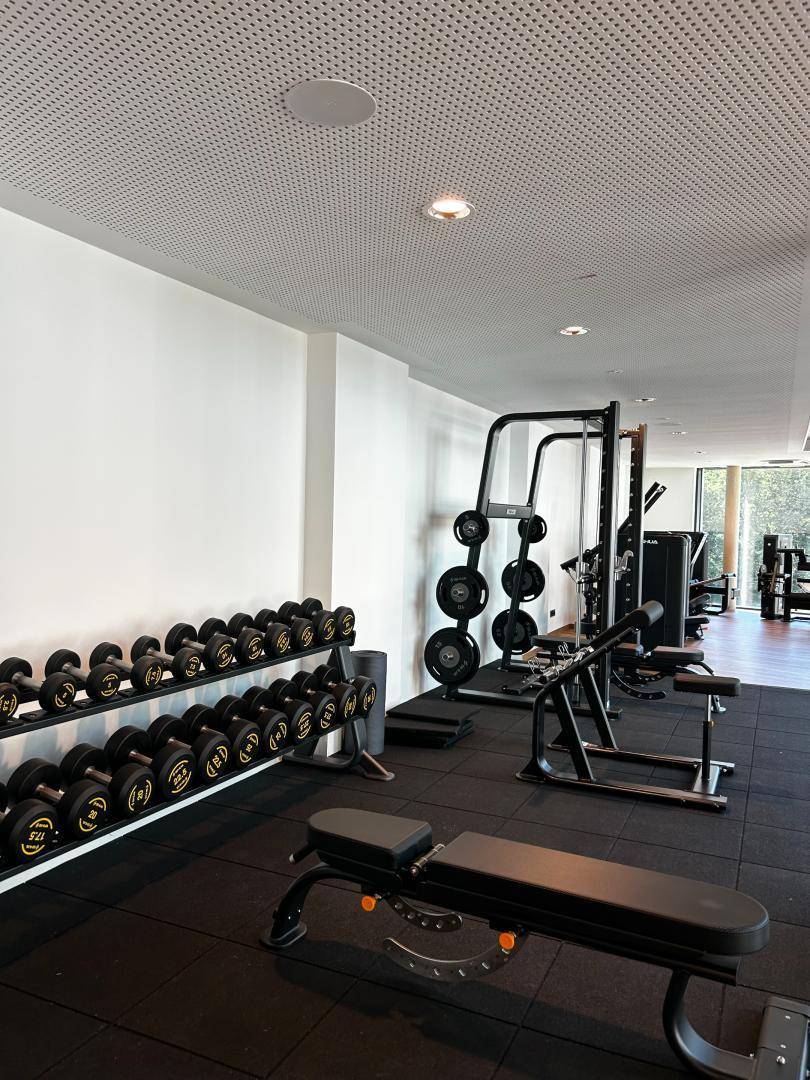 Fitnessbereich mit Hantelablage, Trainingsbänken und Gummiboden für intensives Training.