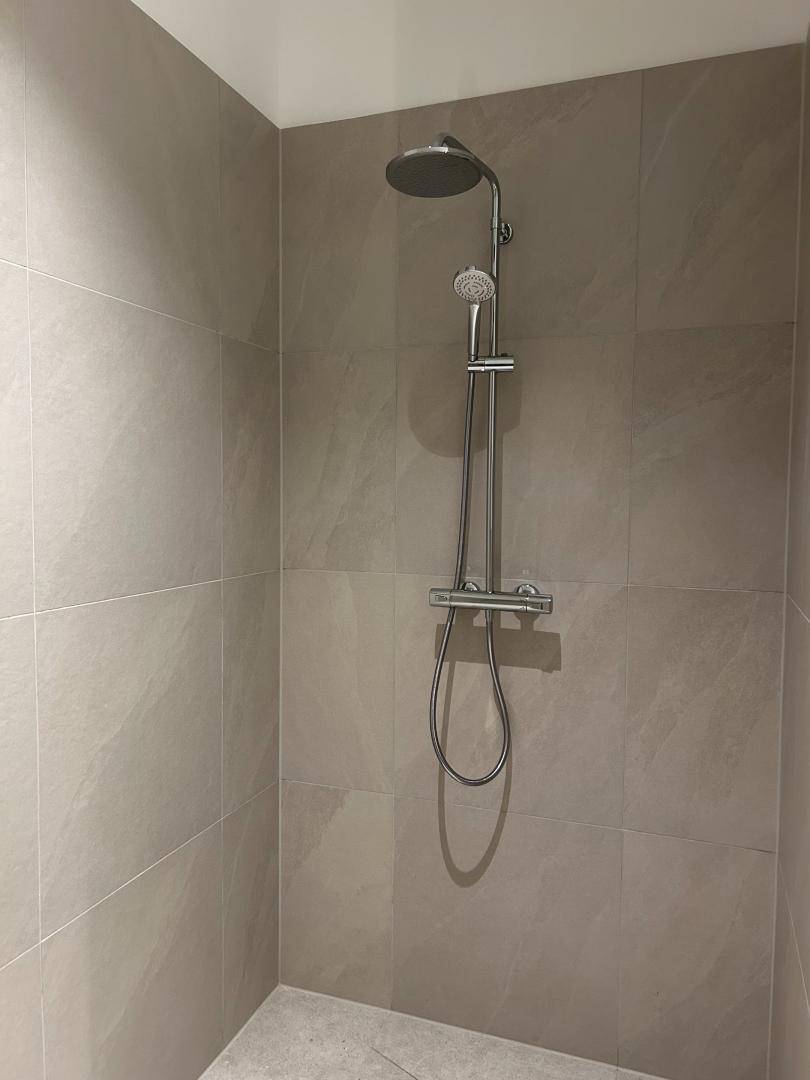 Moderne Duschkabine mit Regendusche und großformatigen grauen Wandfliesen.