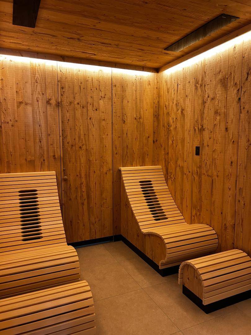 Entspannungsbereich mit ergonomischen Holzliegen und indirekter Beleuchtung in der Wellness-Anlage.