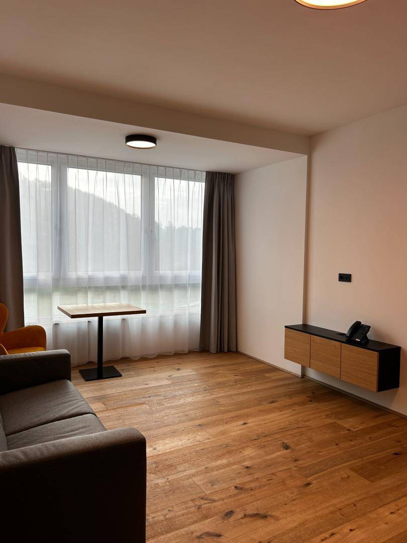 Geräumiges Wohnzimmer mit Holzboden, großen Fenstern und einem modernen Wandregal für Unterhaltung.