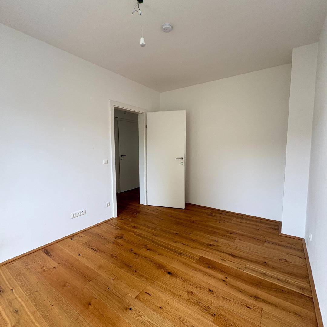 Leeres Zimmer mit Eichenparkett und weiß gestrichenen Wänden, bereit zum Einzug.