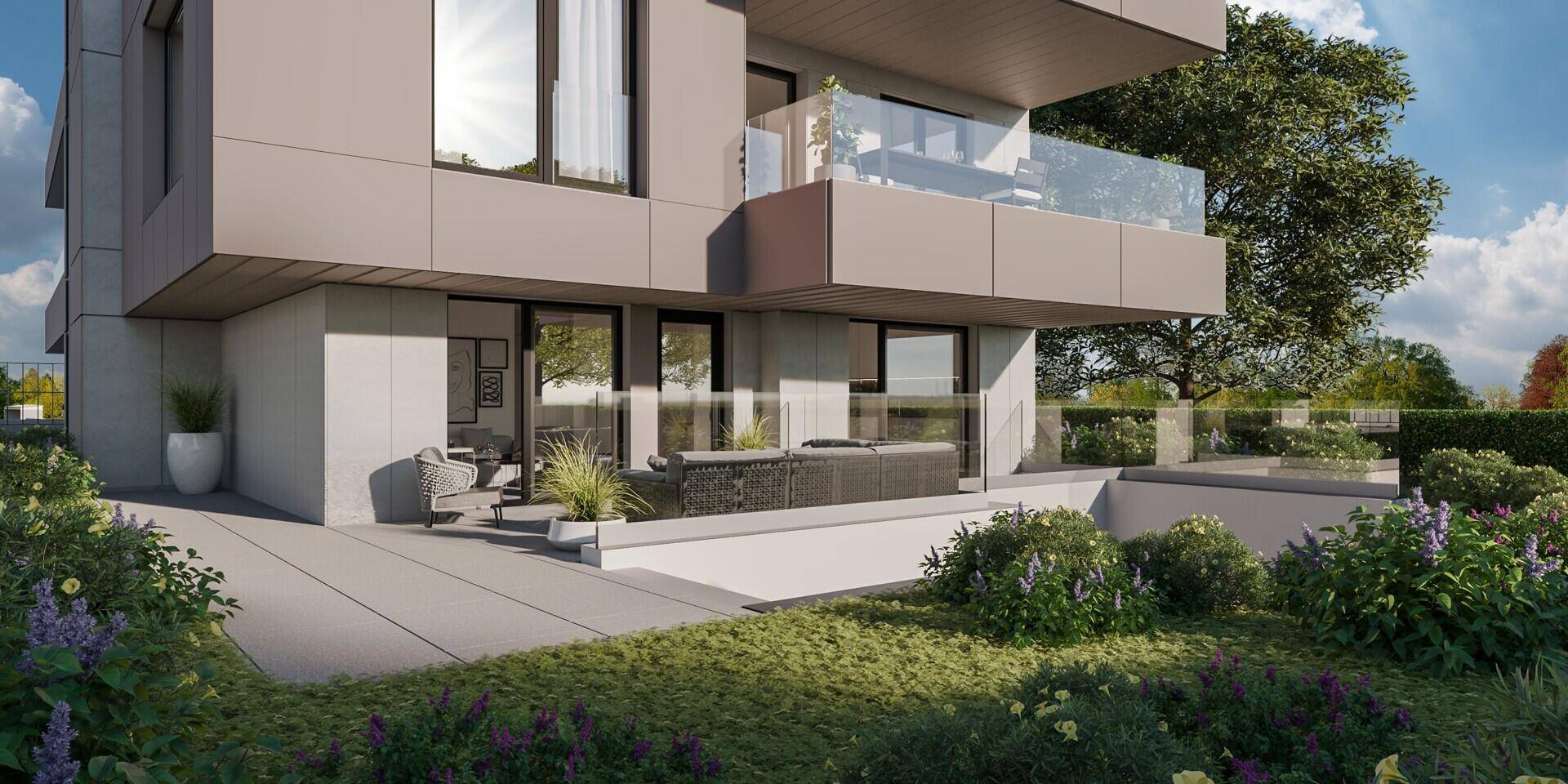Moderne Terrasse mit Lounge-Möbeln und gepflegtem Gartenbereich an einem Neubau.