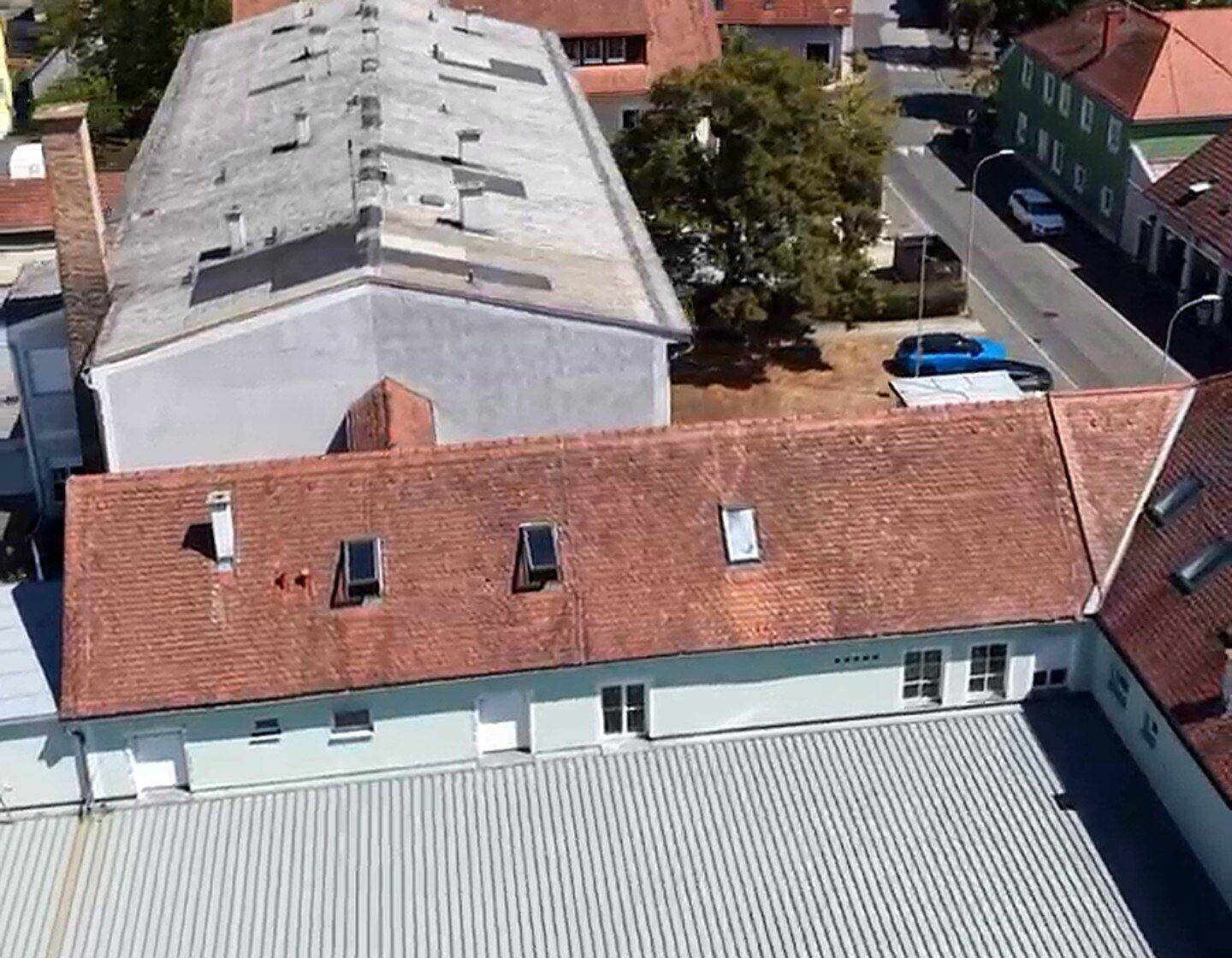 Überblick aus der Vogelperspektive auf die Dächer der Gebäude und die umliegende ländliche Bebauung.