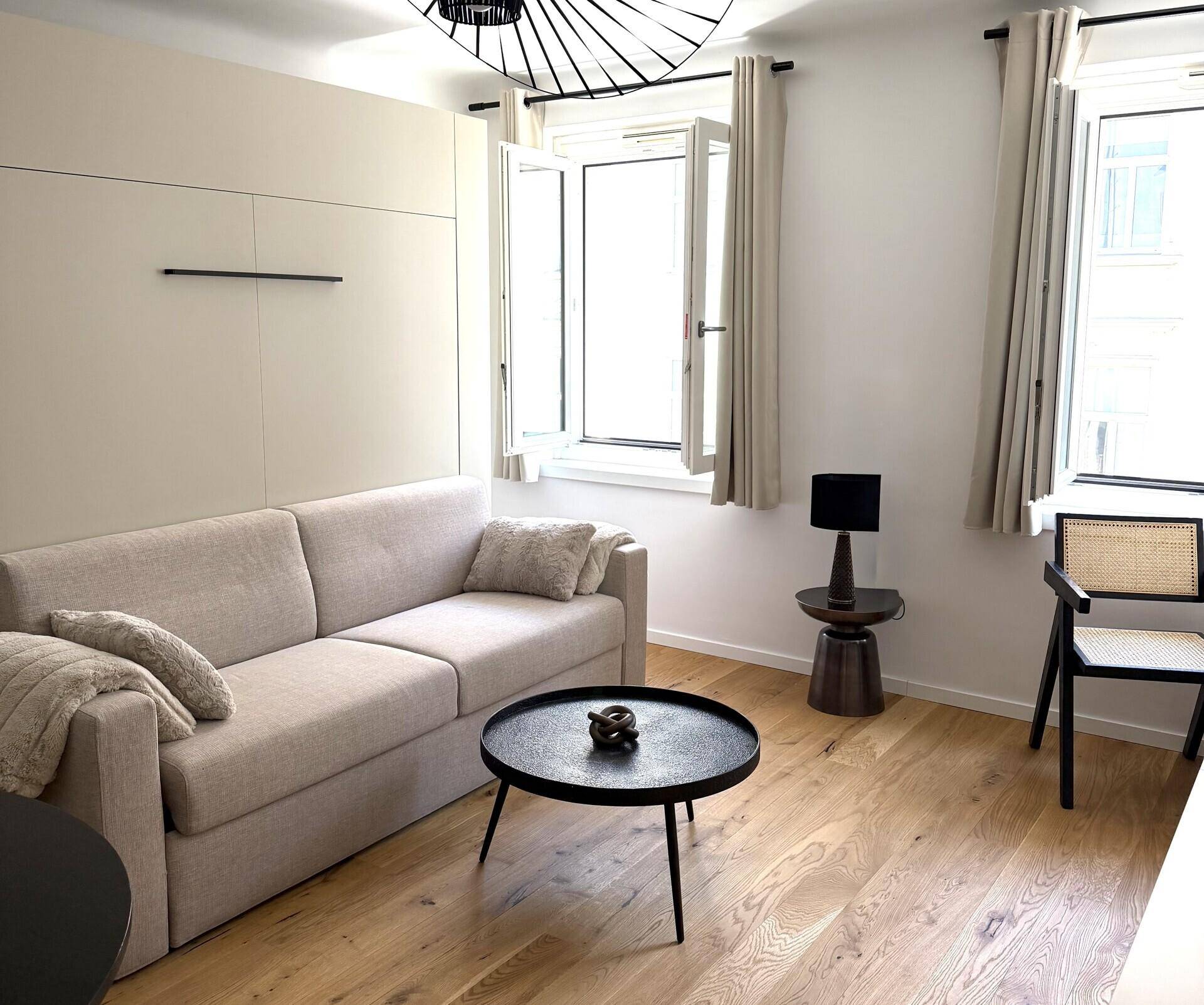 Heller Wohnraum mit bequemem Sofa, Couchtisch und zwei Fenstern für viel Tageslicht.