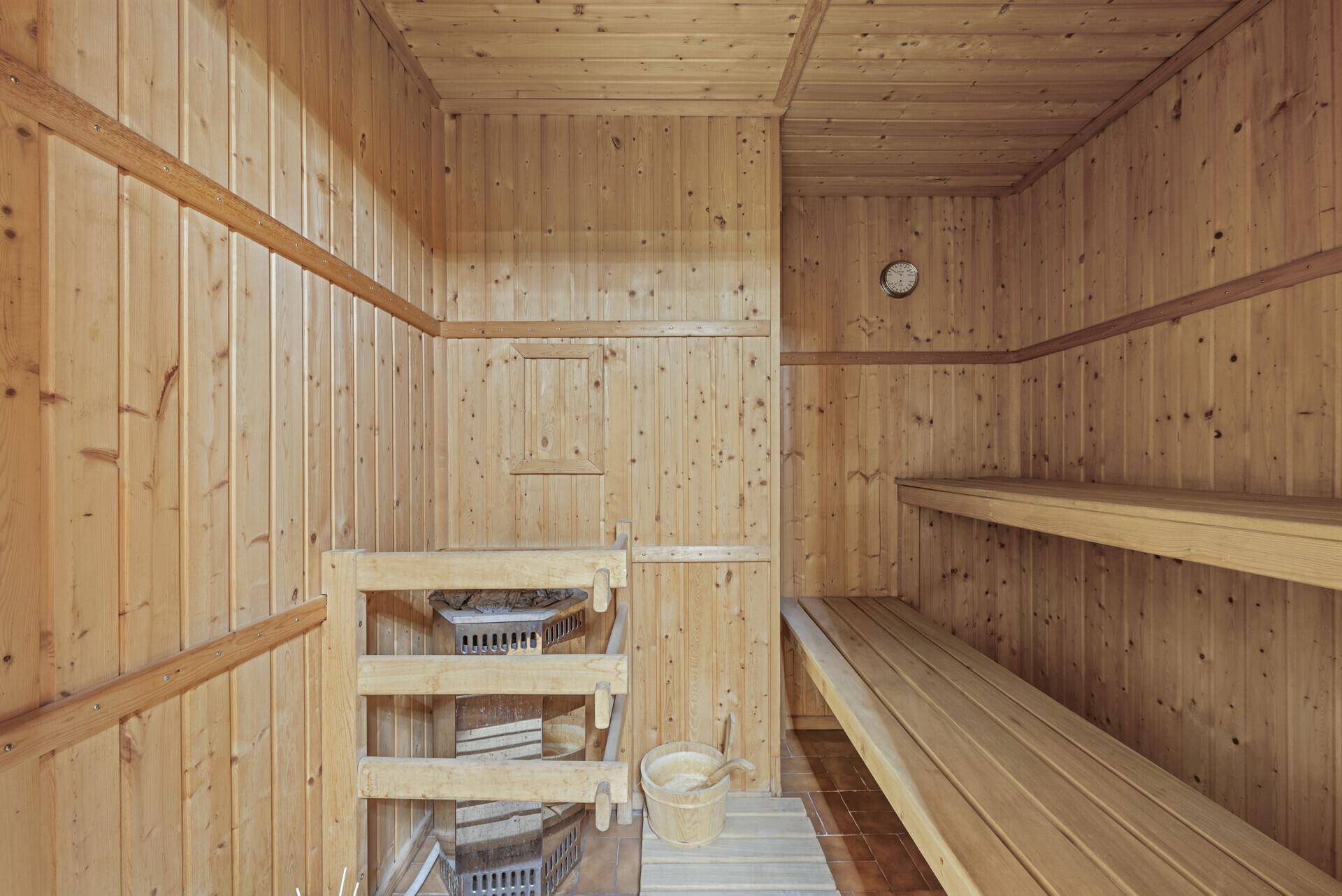Traditionelle Holzsauna mit Bänken und Saunaofen für Entspannung.