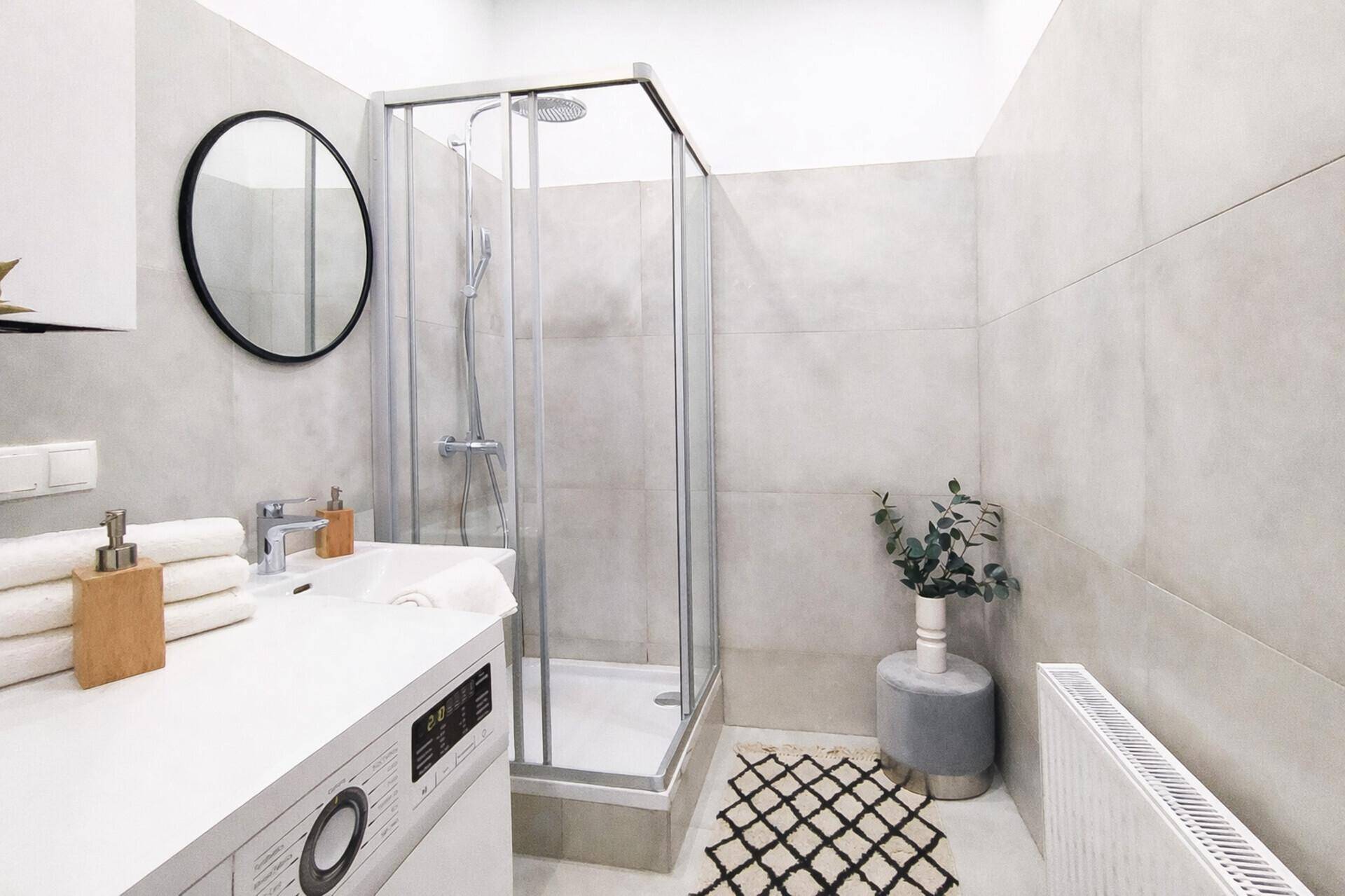 Modernes Badezimmer mit Duschkabine, großformatigen Fliesen und integrierter Waschmaschine.
