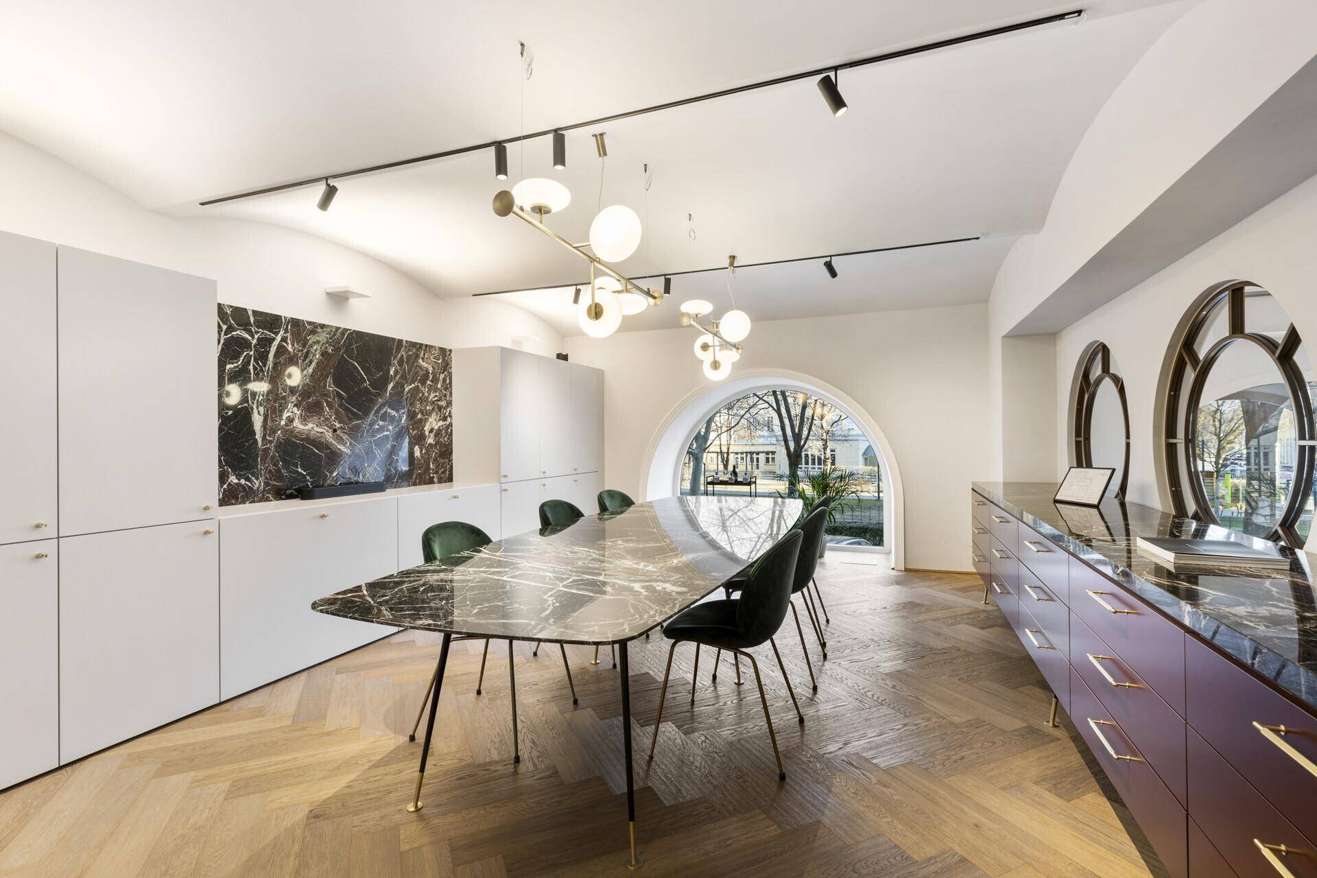 Eleganter Besprechungsraum mit Marmortisch, modernen Leuchten und gewölbtem Fenster.