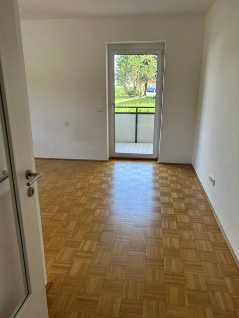 Heller Raum mit Parkettboden und direktem Zugang zu einem Balkon.