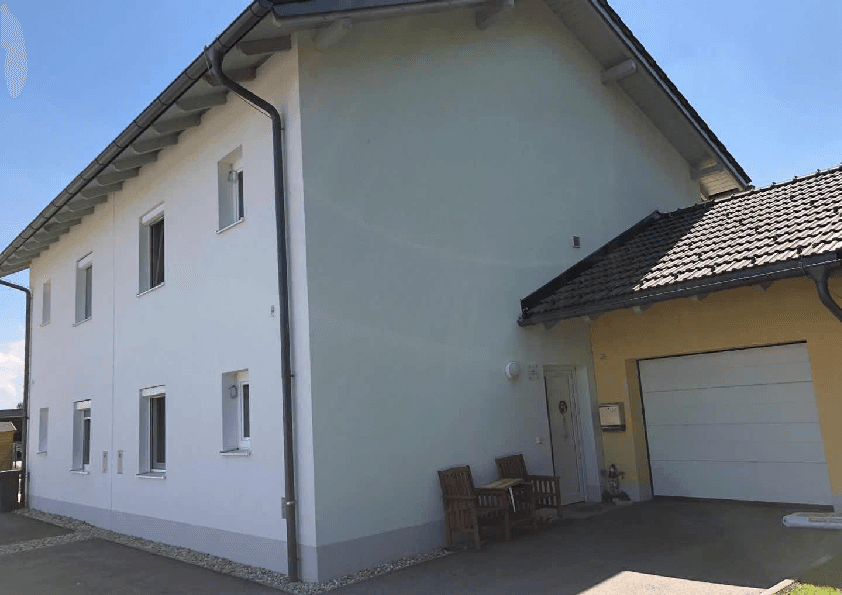 Seitenansicht des modernen Hauses mit Garage, Einfahrt und dem Eingangsbereich bei Tageslicht.