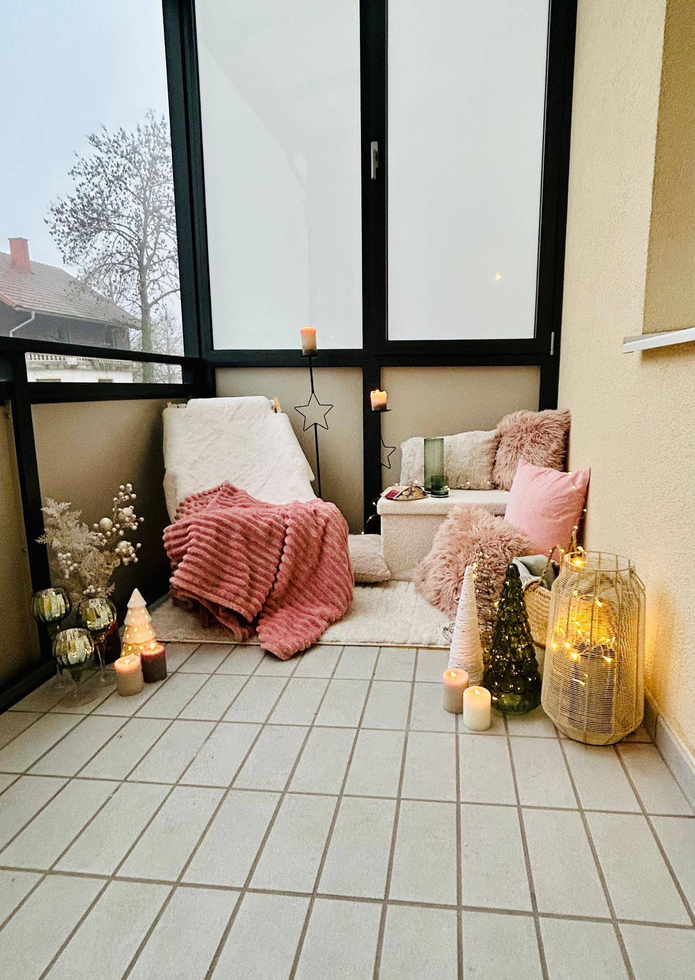 Gemütlicher Balkon mit Fliesenboden, Sitzgelegenheiten und festlicher Dekoration für Entspannung.