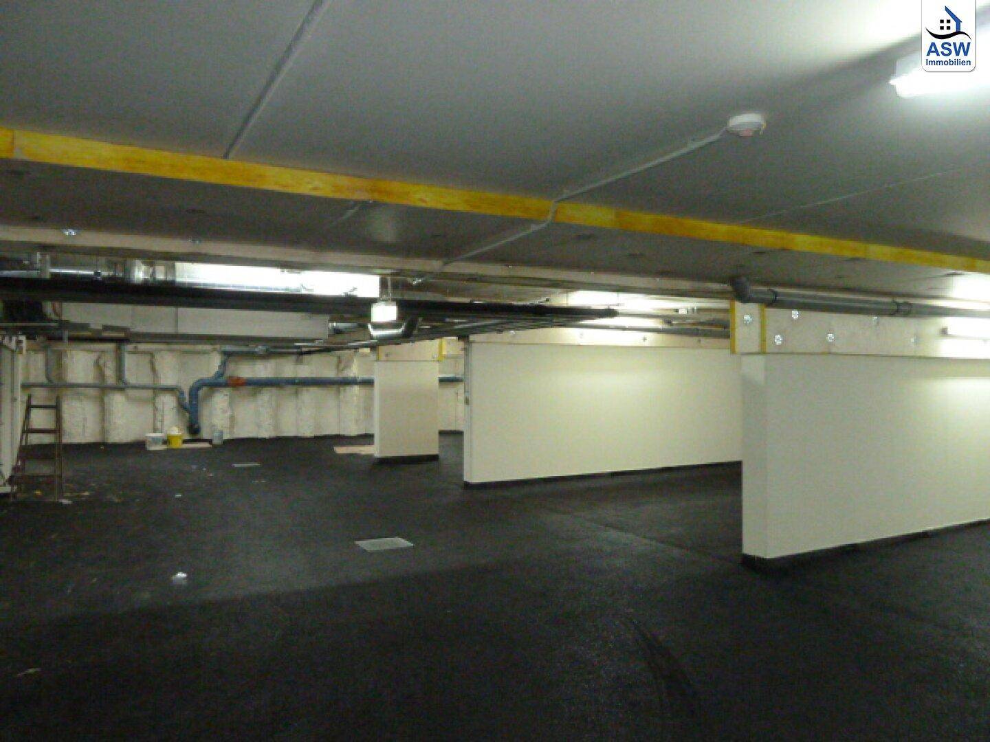 Funktionaler Kellerbereich mit sichtbaren Leitungen und ausreichend Platz für verschiedene Nutzungen, inklusive Parkmöglichkeiten.
