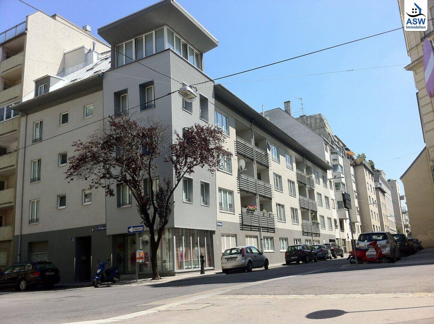 Moderne Wohnhausfassade mit Balkonen und großen Fenstern in urbaner Umgebung.