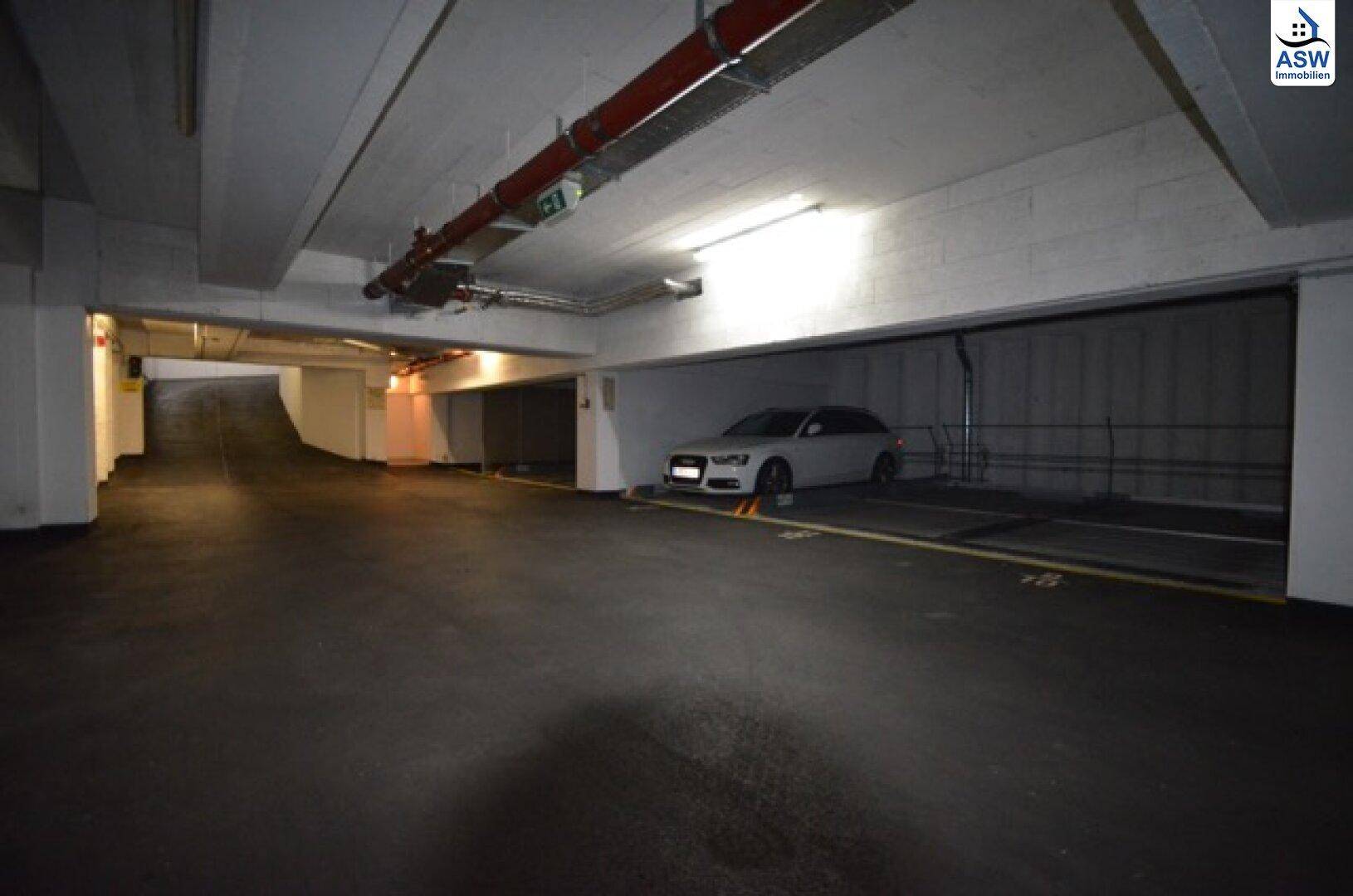 Helle Tiefgarage mit einem geparkten Fahrzeug und Zufahrtsbereich.