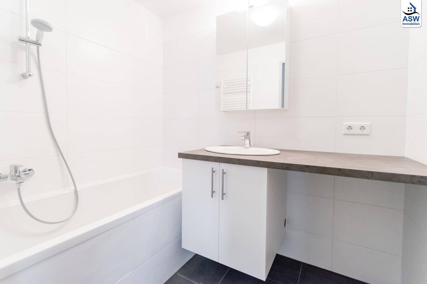 Modernes Badezimmer mit Badewanne, Waschbecken und Spiegelschrank in hellen Farben.