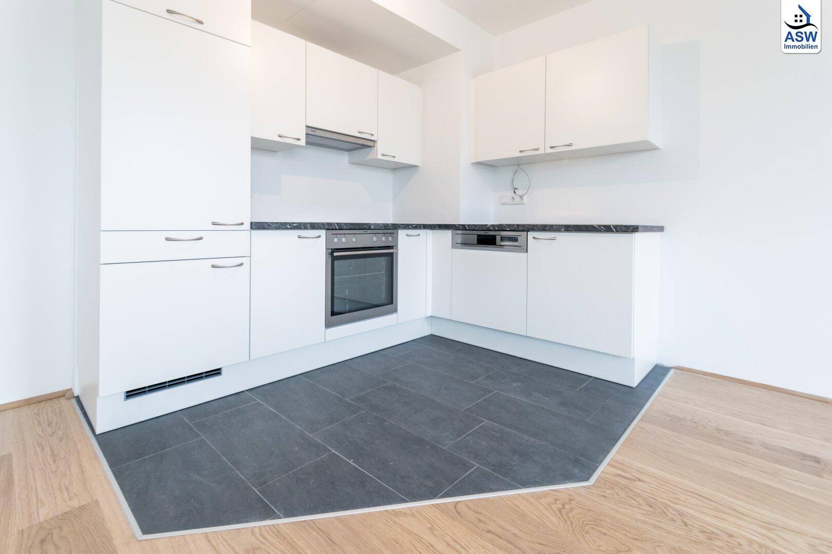 Moderne Einbauküche mit weißen Fronten, dunkler Arbeitsplatte und integrierten Geräten.