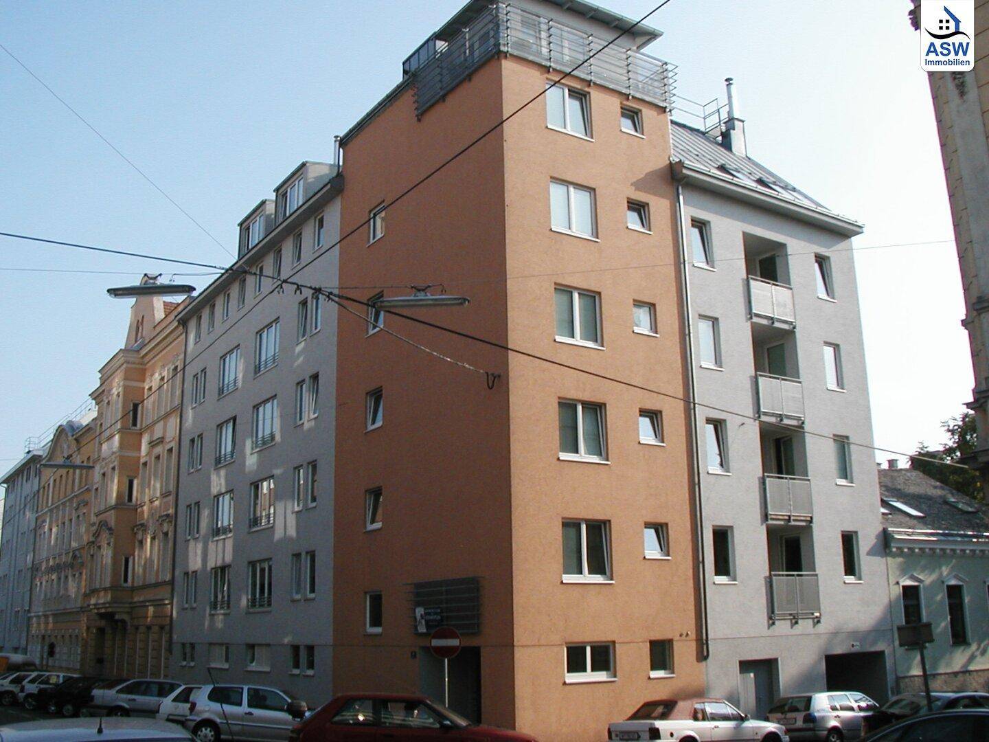 Mehrstöckiges Wohngebäude mit moderner Fassade in Braun- und Grautönen.