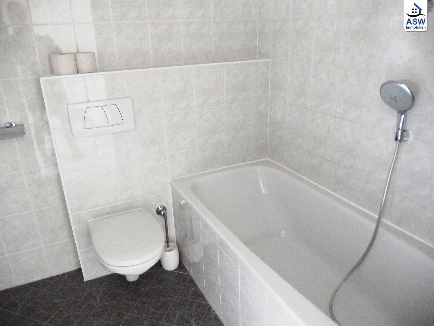 Gefliestes Badezimmer mit Badewanne und Wand-WC.