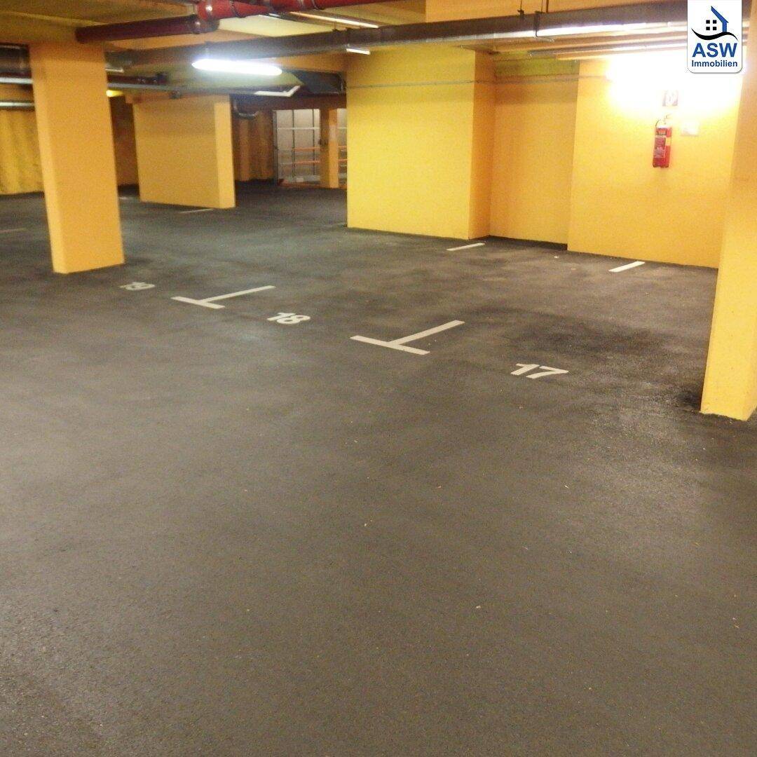Tiefgarage mit markierten Stellplätzen und gelben Wänden, die eine funktionale Parkumgebung bietet.
