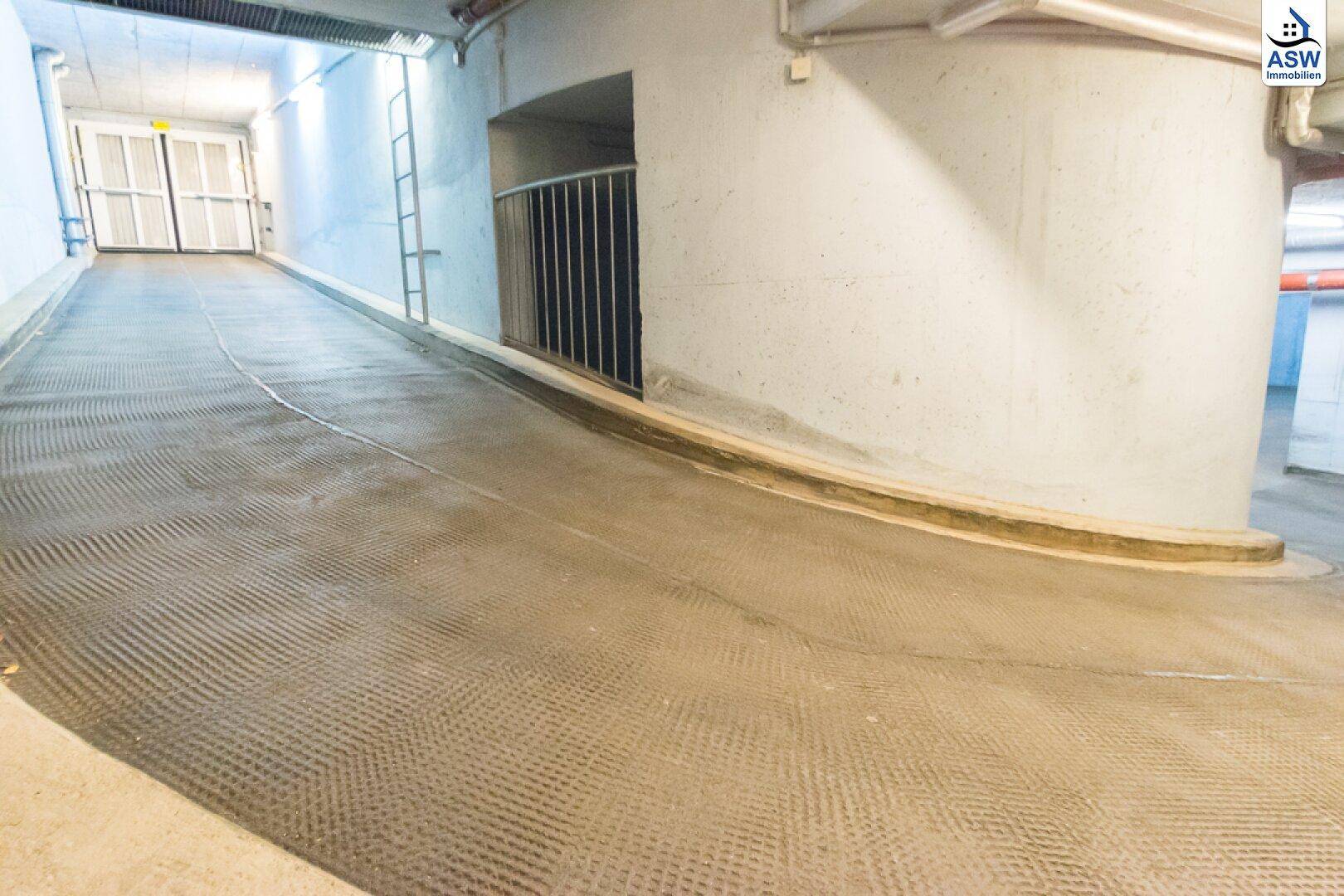 Ausfahrtrampe einer Tiefgarage mit rutschfester Oberfläche und Betonwänden.