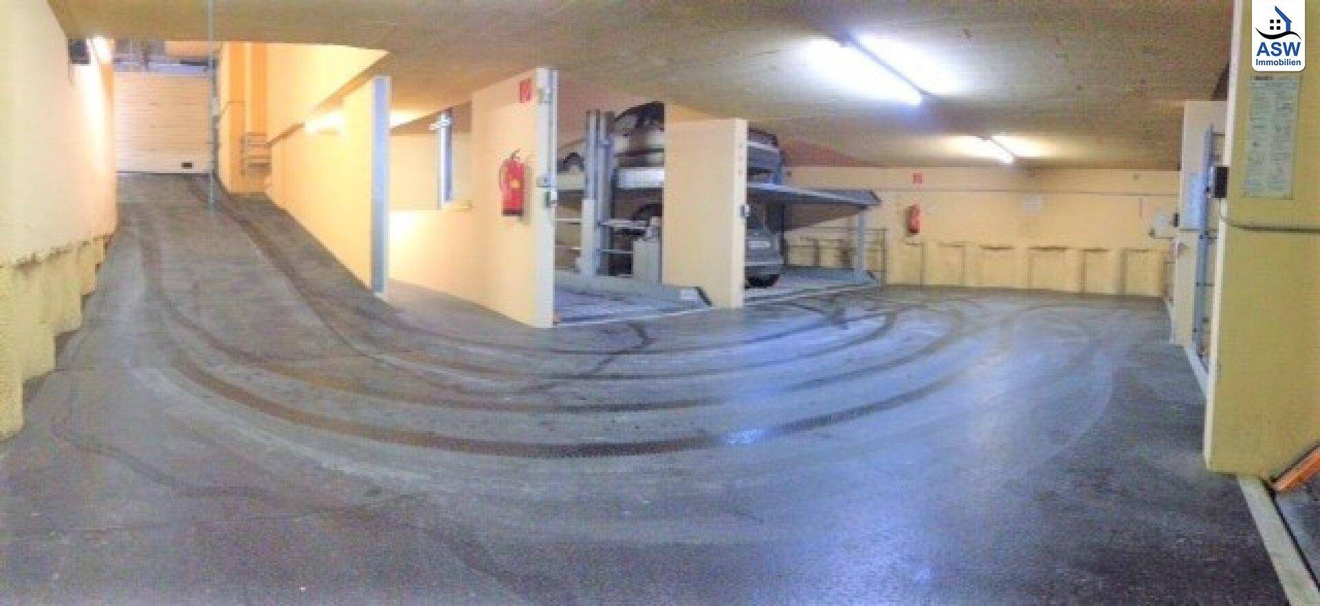 Geräumige Tiefgarage mit Zufahrtsrampe und Autohebebühnen, die zusätzlichen Parkraum bieten.