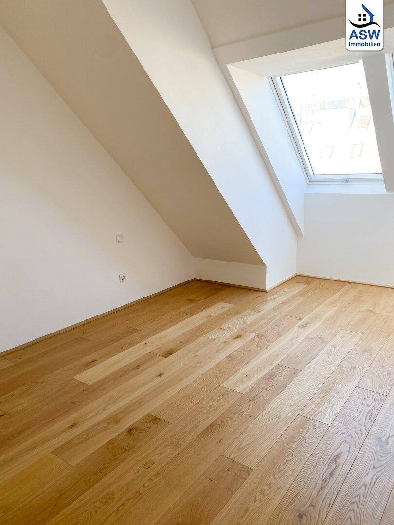 Lichtdurchfluteter Raum mit Holzboden, weißen Wänden und einem großen Dachfenster.