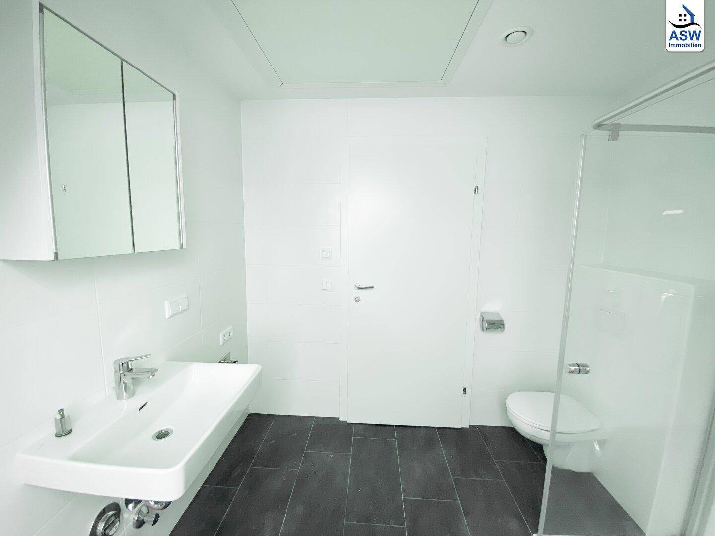 Helles Badezimmer mit modernem Waschbecken, Toilette, Duschbereich und Spiegelschrank.