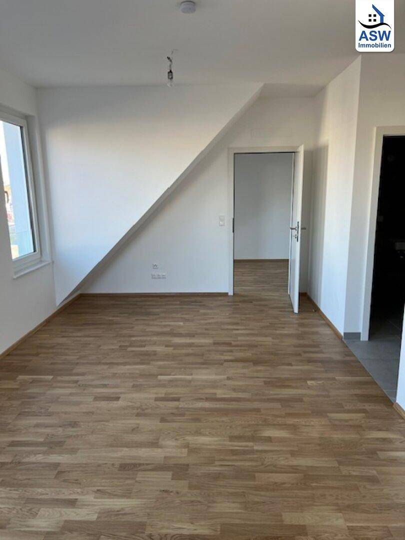 Heller Raum mit Dachschräge, Laminatboden und Fenster für viel Tageslicht.