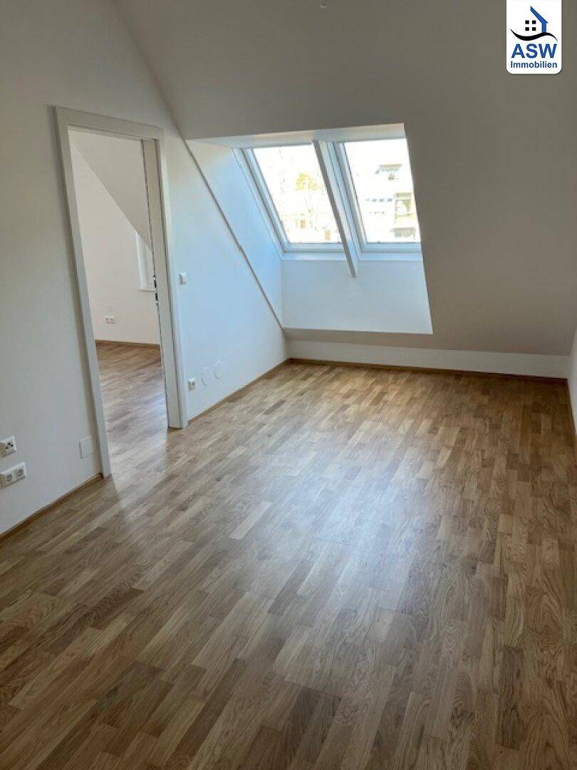 Lichtdurchfluteter Raum mit Dachschräge und zwei Dachfenstern.