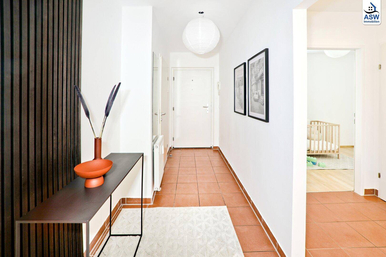 Eingangsbereich mit Terrakotta-Fliesen, weißer Tür und Blick in ein Kinderzimmer.